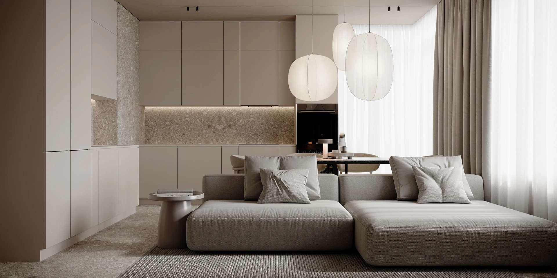 Phòng khách liên thông bếp phong cách tối giản với sofa xám, tủ bếp màu kem phẳng và đèn thả giấy.